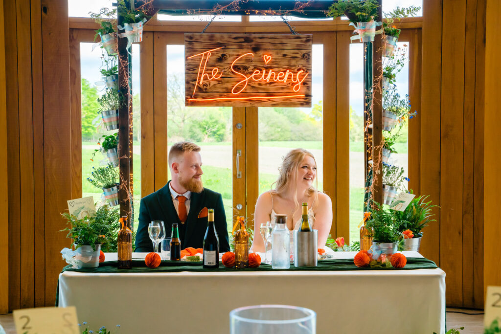 Wedding couple at decorated reception table indoors at The Out Barn.