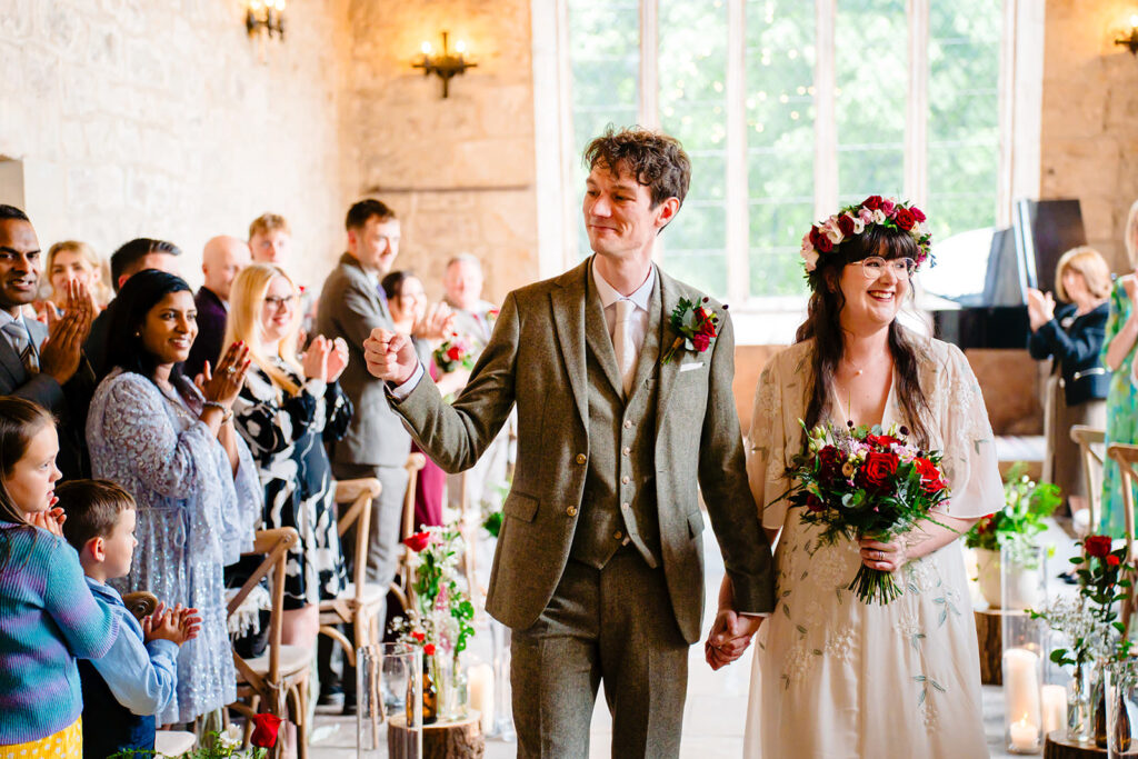 Newlyweds walking hand in hand in the Yorkshire Dales outside the Priests House