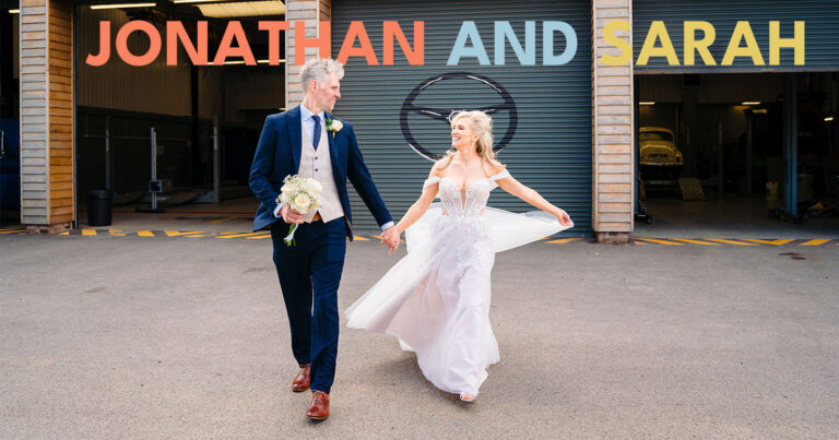 Wedding couple holding hands, industrial backdrop.