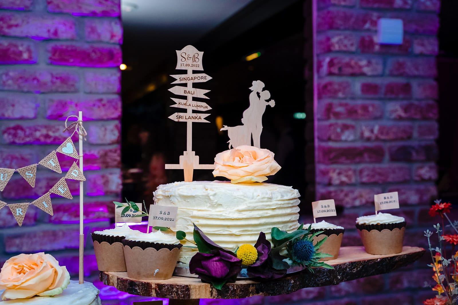 Wedding cake with directional sign cake topper and floral decorations