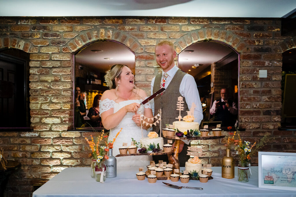 Bride and groom cutting wedding cake at rustic brick venue